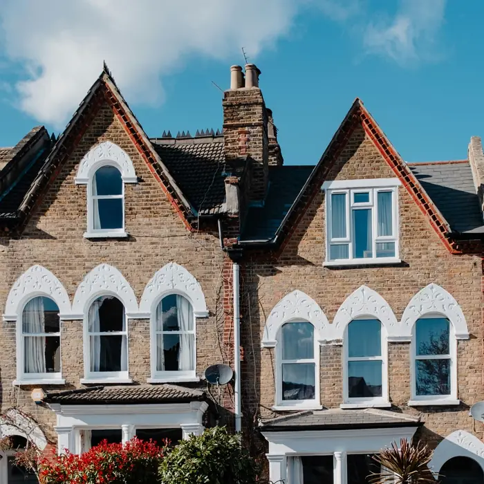 A row of brick terraced houses with arched white window surrounds