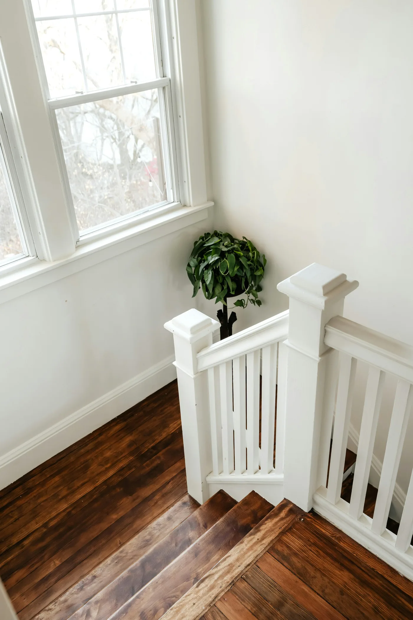 A white-painted staircase with square spindles beside a sash window